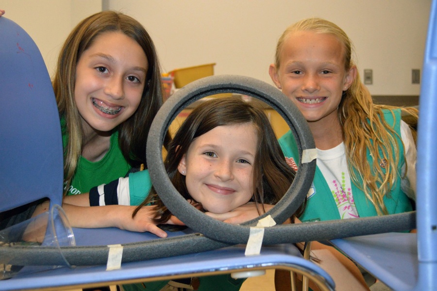 Three girl scouts smile as they participate in scouts day programs.