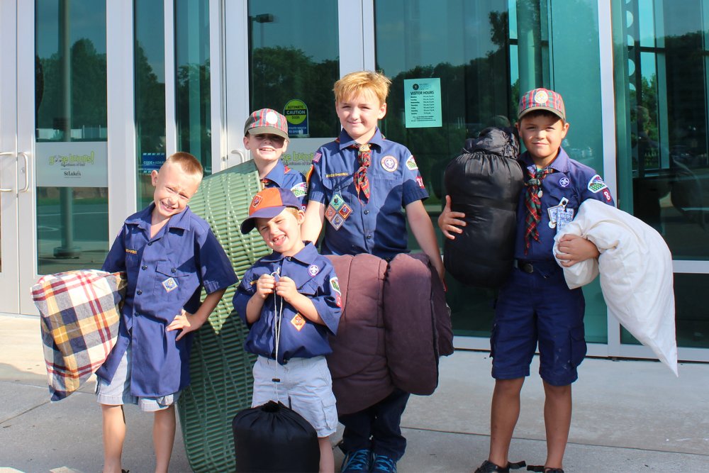 Five cub scouts smile outside of Da Vinci Science Center as they attend scout camp-ins.