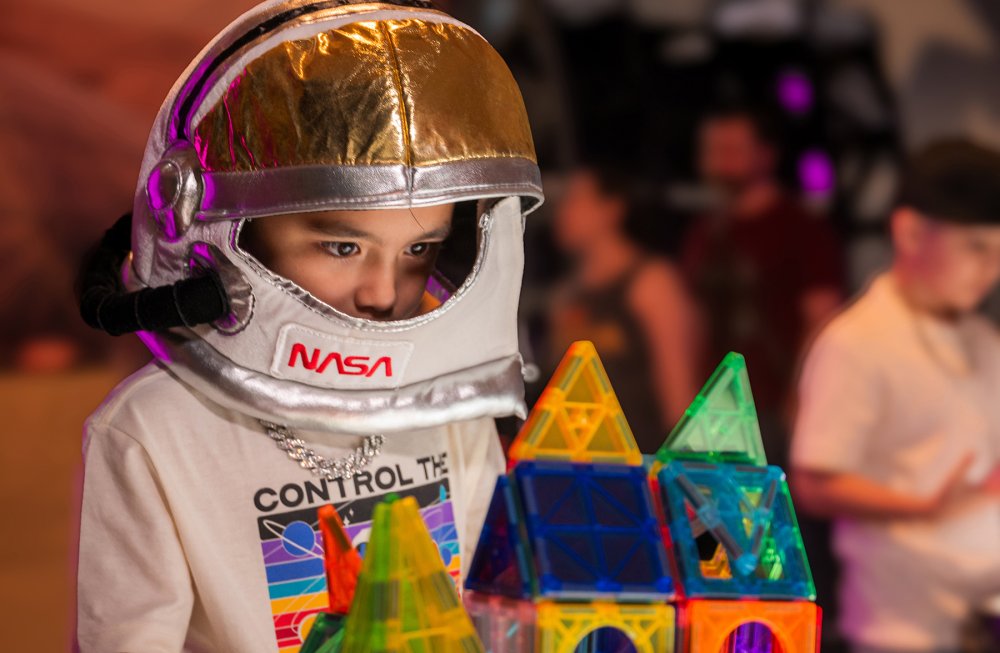 A young boy wearing a plush space helmet visits Mission: Astronaut.